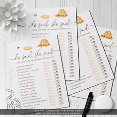 three sheets of paper with gold foil on them next to a pen and white flower