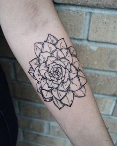 a black and white flower tattoo on the left arm, it looks like a succulent