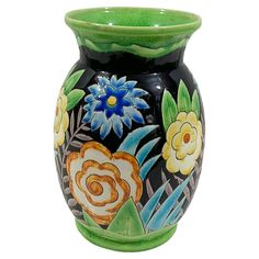 a black vase with flowers painted on the side and green rimming it's sides