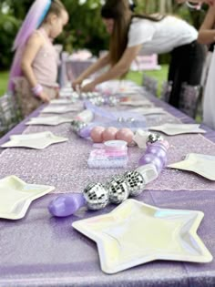 the table is set up with purple and white plates, silver beads, and star shaped napkins