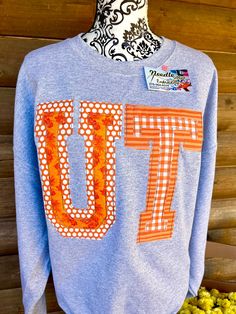 a blue sweatshirt with an orange and white number seventy on the front, sitting next to some yellow flowers