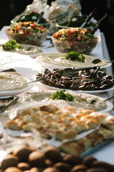 a buffet table filled with lots of different types of food on plates and serving utensils