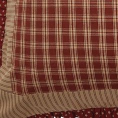 a close up of a pillow on a bed with red and white checkered sheets