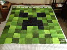 a bed with a green and black quilt on top of it