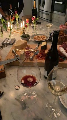 wine glasses and food on a table with candles in the middle, surrounded by other items