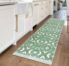 a green rug in the middle of a kitchen with white cabinets and countertops