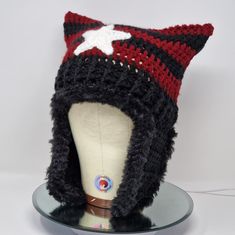 a crocheted hat with a white star on the front and red, black, and gray stripes