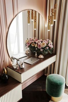 a vanity with flowers on it and a laptop in front of a round mirror above