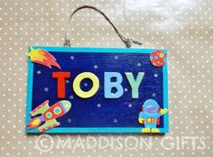 a wooden sign that says tobby with an astronaut and rocket ship on it