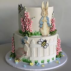 a three tiered cake decorated with rabbits and flowers