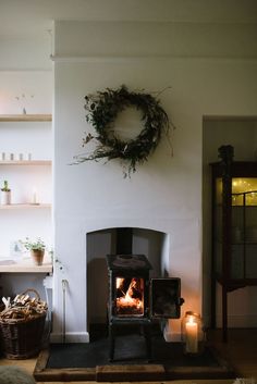 a fireplace with a wreath on the wall above it and candles in front of it