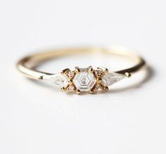 three stone ring in yellow gold and white diamonds, set on a plain surface with two smaller stones