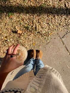 a person with their feet on the ground holding a wine glass in front of them