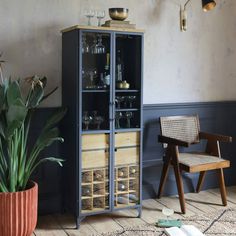 a room with a chair and a cabinet in the corner next to a potted plant