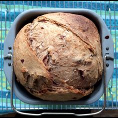 a loaf of bread sitting in a pan on top of a blue table cloth next to a cooling rack