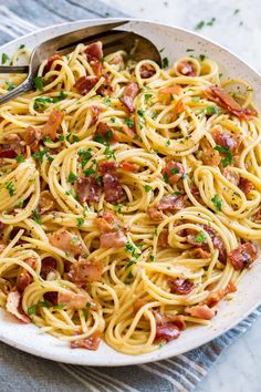 a plate full of pasta with bacon and parsley on the side, ready to be eaten