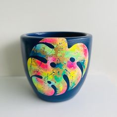 a blue vase with colorful designs painted on the outside and inside, sitting on a white surface