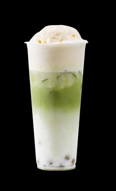 a tall glass filled with ice cream and cucumber on the rim, against a black background