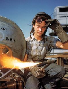 a woman wearing goggles sitting on top of a metal object with a flame coming out of it