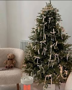 a small christmas tree is decorated with ribbons and bows, while a teddy bear sits next to it