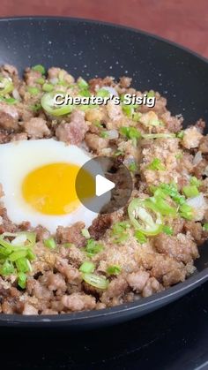 an egg frying in a skillet with green onions and meat on it's side