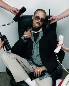 a woman sitting in a chair with two hands on her head and one holding a phone to her ear