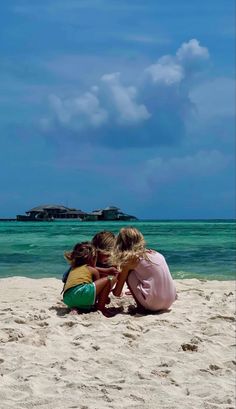 two children sitting on the beach looking out to sea