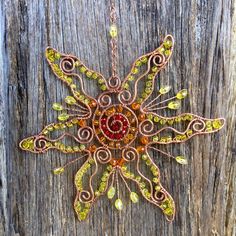 a necklace made out of wire and beads on a wooden surface with an orange bead in the center