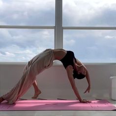 a woman is doing yoga in front of a window with her hands on the ground