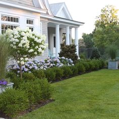 a white house with lots of flowers in the front yard