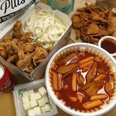 an assortment of food including pasta, chicken wings and coleslaw are on the table