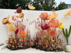 an arrangement of flowers is displayed in front of a white wall with the words happy birthday written on it