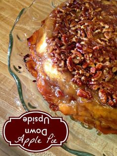 an apple pie with pecans and caramel toppings on a clear glass plate