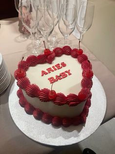 a heart shaped cake sitting on top of a table next to wine glasses and plates