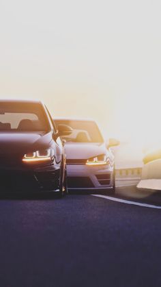 two cars are driving down the road at sunset