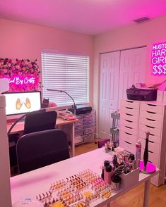 a desk with lots of cosmetics on it and a pink neon sign in the background