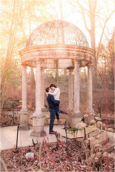 an engaged couple standing in front of a gazebo