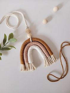 a white and brown necklace next to some green leaves on a white surface with beads