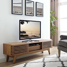 a flat screen tv sitting on top of a wooden entertainment center in a living room