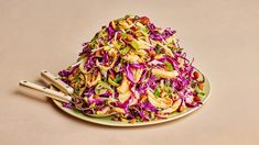 a plate full of coleslaw with chopsticks next to it on a table