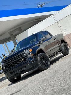 a black truck parked in front of a gas station