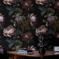 a table with a clock on it next to a flower wallpapered wall in a room