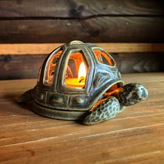 a small tortoise shell with a lit candle inside on a wooden table next to wood planks