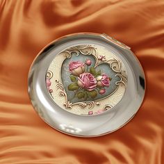 there is a plate with roses painted on the side and in the shape of a heart