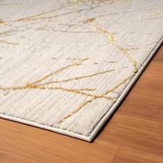 a white and gold area rug on a wooden floor with a wood flooring surface