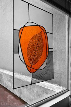 a stained glass window with an orange leaf on it