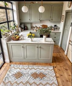 a kitchen with green cabinets and an area rug in front of the counter top that has flowers on it