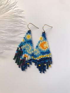 a pair of beaded earrings with feathers on the back and one earring made out of beads