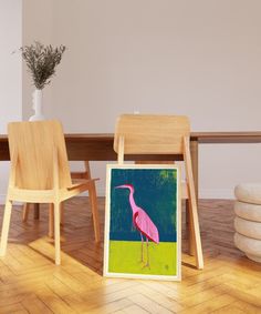 a pink flamingo standing in front of a table with two chairs and a vase