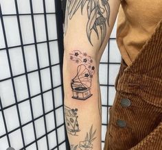 a person with a tattoo on their arm holding a coffee cup and record player in front of them